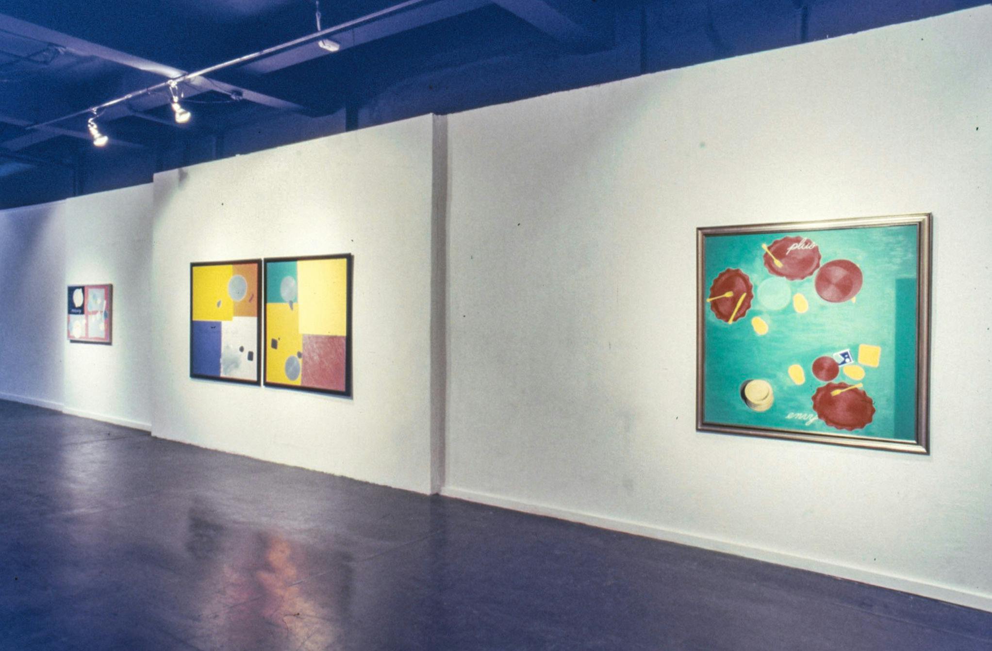 Three paintings on the walls of a gallery. The paintings are in square frames of different sizes and colours. All of the paintings show different sets of dishes from above, on colourful backgrounds.