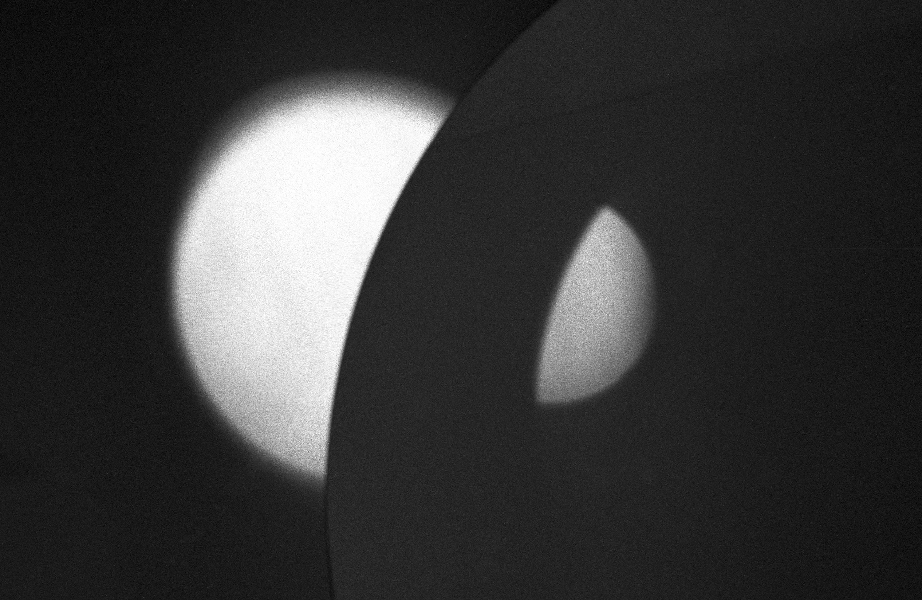 An abstract black and white image depicting two semi circles of light on a dark background. 